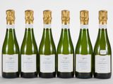 six bouteilles de vin sont alignées sur une surface blanche