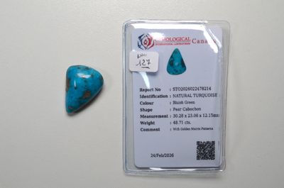 une pierre bleu turquoise en forme de cœur posée à côté d'une carte sur une surface blanche
