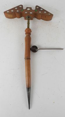a close up of a clock with a wooden handle on a white surface