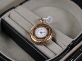 une montre de poche en or dans un écrin posé sur une surface noire
