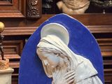 une statue représentant une femme tenant un bébé dans ses bras, à côté d'une plante en pot