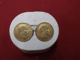 a close up of two gold coins sitting on top of a white box