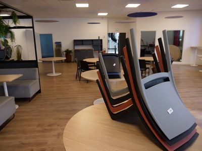 tables and chairs in an office with a laptop on top of them