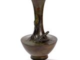a bronze vase that is sitting on a white surface