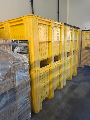 Plusieurs caisses jaunes sont empilées les unes sur les autres dans un entrepôt