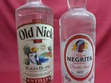 two bottles of old nick vodka sit side by side on a pink background