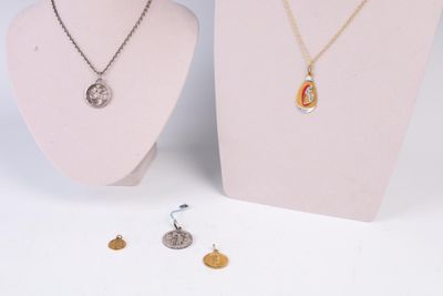 deux colliers et une pièce de monnaie posés sur un présentoir pour mannequin