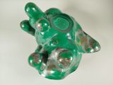 une figurine de tortue verte posée sur une surface blanche