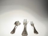 three forks and a spoon sitting on a table