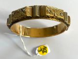 a close up of a gold bracelet with a tag on it