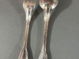 two silver spoons and a fork sitting on a table