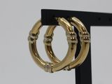 a close up of a pair of gold hoop earrings on a black stand