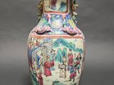 a vase with a painting on it sitting on a table