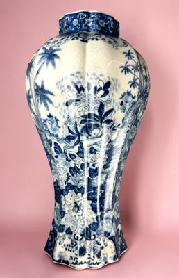 un vase bleu et blanc posé sur une surface rose