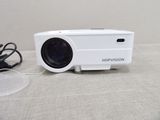 un projecteur blanc posé sur une table à côté d'un chargeur