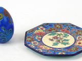 une assiette bleue et un œuf bleu posés l'un à côté de l'autre