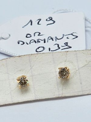deux paires de boucles d'oreilles en or et diamants posées sur un morceau de papier