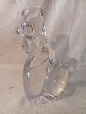 une figurine en verre transparent représentant un chien, posée sur une table
