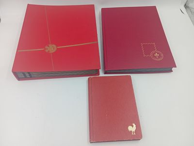 Trois livres rouges sont posés les uns à côté des autres sur une table.