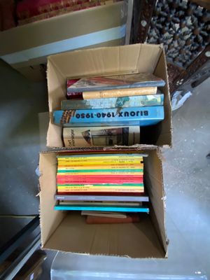 de nombreux livres dans une boîte en carton posée sur le sol