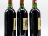 three bottles of wine are lined up on a white surface