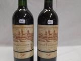 two bottles of wine sitting on top of a table next to each other