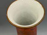 a close up of a red and white vase on a stand