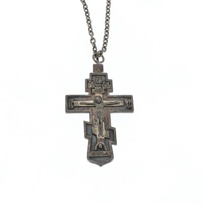 l'image d'une croix en argent suspendue à une chaîne, sur fond blanc
