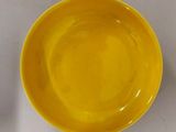 un bol jaune et une assiette jaune posés sur une table blanche