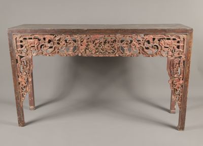 une vieille table en bois dont le plateau est orné de sculptures