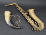an old saxophone and horn are sitting on a black surface