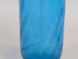 a blue glass vase with writing on it on a table