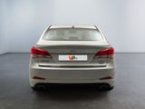 the back of a silver car in a room with a white wall