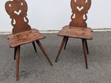 two wooden chairs sitting next to each other in a parking lot