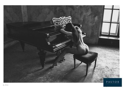 black and white photograph of a naked woman sitting at a piano