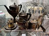 un plateau sur lequel sont posées des théières, des tasses et des soucoupes en argent
