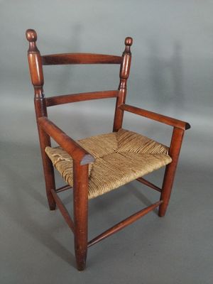 an old wooden chair with a woven seat on a gray background