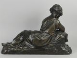 an antique bronze statue of a woman sitting on a rock