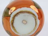 a close up of an orange and white vase on a white surface