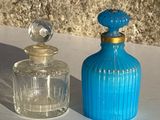 une bouteille en verre bleue à côté d'une bouteille en verre transparent, posées sur une table