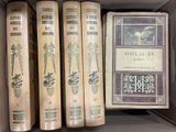 Plusieurs livres se trouvent dans une boîte posée sur une étagère, à côté d'un livre.