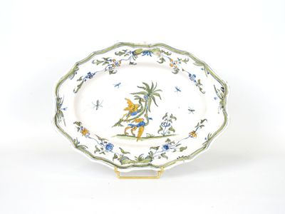 une assiette décorée d'un oiseau, posée sur un socle