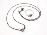 Photo d'un collier et d'une bague avec une chaîne sur fond blanc