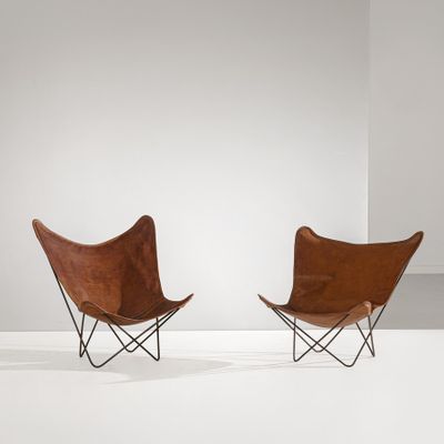 une paire de fauteuils papillon en cuir dans une pièce blanche