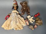 une petite poupée avec un ours en peluche et d'autres jouets posés sur une table