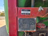 un gros plan d'un tracteur rouge et vert sur lequel est accrochée une pancarte
