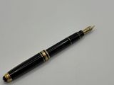 un stylo-plume noir et doré posé sur une table blanche