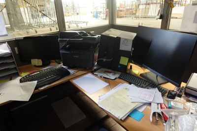 une photo d'un bureau encombré avec deux écrans et un clavier