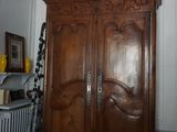 une grande armoire en bois placée dans un coin d'une pièce où se trouve un radiateur