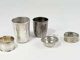 quatre tasses en argent et une cuillère en argent posées sur un plateau blanc